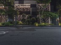 the street outside of the building at night time with the lights on and no cars around it