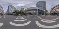 a reflection in a fish eye lens shows buildings on either sides of a road with a pedestrian crossing