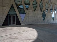 there is a large glass building with many windows and a large stone walkway outside it