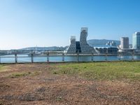 view of a city and water from the other side of a fence with grass growing in it