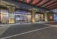 the outside of a building with some glass doors in it's front area at night