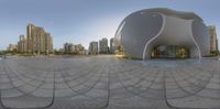 a circular photo of a building surrounded by tall buildings and a park area with a fountain