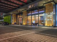 a building with large glass doors and illuminated windows in front of it at night time