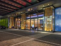 a building with large glass doors and illuminated windows in front of it at night time