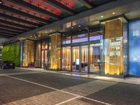 a building with large glass doors and illuminated windows in front of it at night time