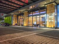 a building with large glass doors and illuminated windows in front of it at night time