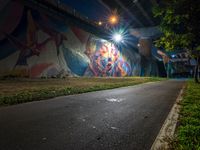 a painting shows a person riding a motorcycle down the road in the city at night