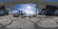 an empty square with two benches next to it on the sidewalk, and a view of city buildings through a fish eye lens