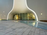 an empty pool that is near the entrance to an office building with an arched roof