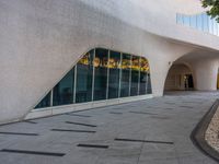 a paved walkway near a building that has a circular window with large glass panels at the entrance