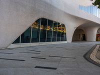 a paved walkway near a building that has a circular window with large glass panels at the entrance