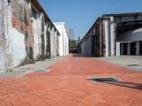 a narrow brick road leading into an old building structure in the city area of miami