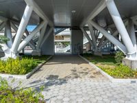 a walkway that is built inside a building surrounded by greenery and flowers on the street