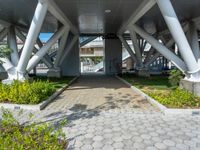 a walkway that is built inside a building surrounded by greenery and flowers on the street