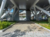 a walkway that is built inside a building surrounded by greenery and flowers on the street