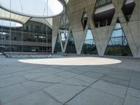 a round concrete structure with several windows is empty in the courtyard at the museum of modern art