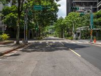 there is a street corner with trees lining the sidewalks and streets, and an empty street is shown in the distance