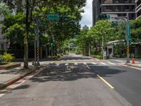 there is a street corner with trees lining the sidewalks and streets, and an empty street is shown in the distance