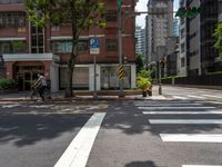 a crosswalk and street sign next to a street with buildings in the background on a clear day