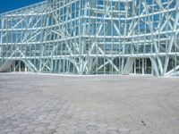 an abstract architecture photo with a large glass building behind it in the foreground and a stone floor outside