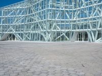 an abstract architecture photo with a large glass building behind it in the foreground and a stone floor outside