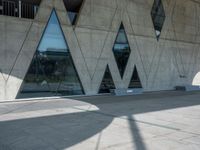 a building with some glass windows and a concrete floor with benches on it and the entrance is large and gray