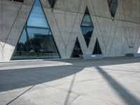 a building with some glass windows and a concrete floor with benches on it and the entrance is large and gray