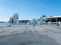 an empty pier on a bright day with the city of vancouver in the distance and some buildings in the background