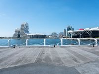 an empty pier on a bright day with the city of vancouver in the distance and some buildings in the background