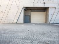 the door to an industrial area is open outside of a building, which has a small window at the entrance and on a side walk way in front