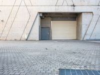 the door to an industrial area is open outside of a building, which has a small window at the entrance and on a side walk way in front