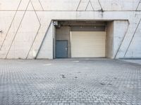 the door to an industrial area is open outside of a building, which has a small window at the entrance and on a side walk way in front