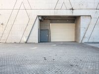 the door to an industrial area is open outside of a building, which has a small window at the entrance and on a side walk way in front