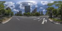 the view of a street in a city from a wide angle, with two traffic lanes in between the road and buildings