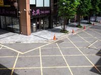 an empty lot has been marked with yellow lines and green trees in the background that are lined with cones