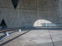 a person riding a skateboard next to an empty wall and building with some windows