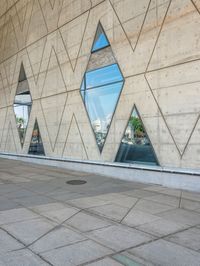 the window reflects the city and trees through the glass of this building as an image of a person riding a bicycle