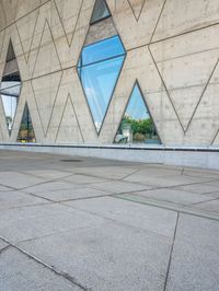 the window reflects the city and trees through the glass of this building as an image of a person riding a bicycle