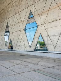 the window reflects the city and trees through the glass of this building as an image of a person riding a bicycle