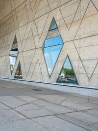 the window reflects the city and trees through the glass of this building as an image of a person riding a bicycle