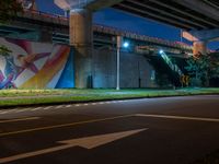 the painted mural above the highway on the side of a building at night with cars driving underneath