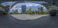 the view from inside an upside down mirror with buildings in the background, and there's a bench in between the building's edge