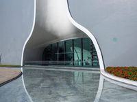 a white curved building has a lot of windows on the outside of it with glass
