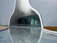 a white curved building has a lot of windows on the outside of it with glass