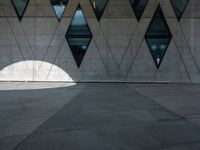 an empty walkway with large triangles on the outside and windows in front of it with an open door