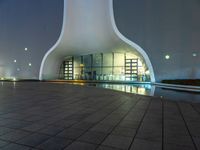 this is a large modern building with an illuminated building on the ground with buildings surrounding it