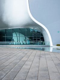 an image of outside view of a building with glass walls and a pool on the ground