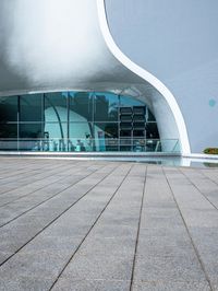 an image of outside view of a building with glass walls and a pool on the ground