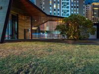 this is an image of a building at night with windows on it and a lot of grass on the lawn