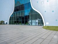 the entrance to a building that is white and blue with geometric shapes on it and grass in front of it